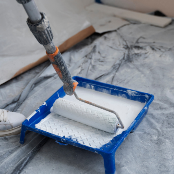 Tabuleiro de pintura azul com tinta branca e um extensor com rolo de pintura